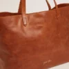 Geantă Pasadena din piele ciocănită lucioasă de culoare bej, cu logo auriu pe partea din față
