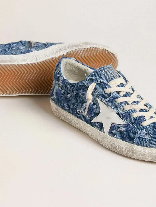 Modelul Super-Star LTD pentru femei, din denim albastru deschis, cu o stea din piele albă și flori brodate