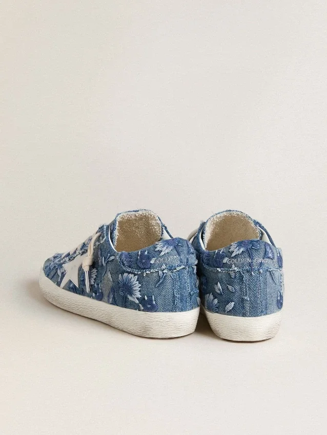 Modelul Super-Star LTD pentru femei, din denim albastru deschis, cu o stea din piele albă și flori brodate